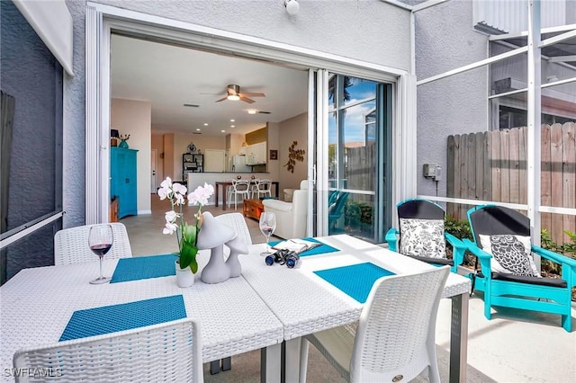 view of patio featuring ceiling fan, fence, outdoor dining area, and outdoor dry bar