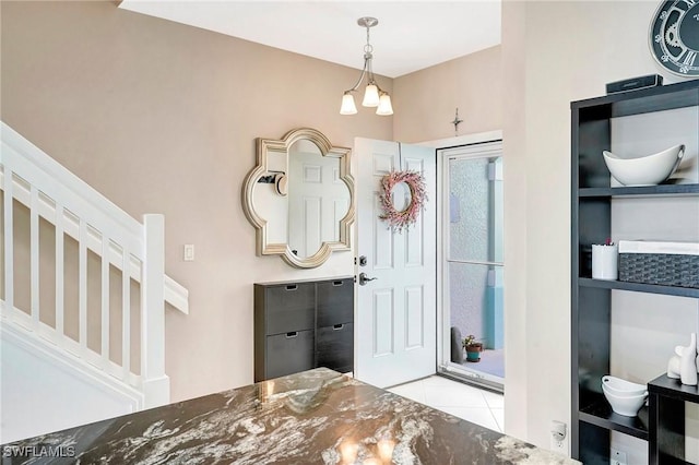 tiled foyer featuring stairs and a chandelier