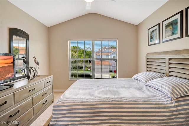 bedroom with a ceiling fan, light colored carpet, vaulted ceiling, and baseboards