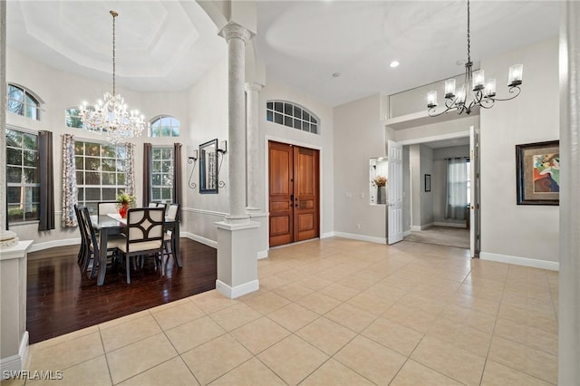 unfurnished dining area with an inviting chandelier, decorative columns, light tile patterned flooring, and baseboards