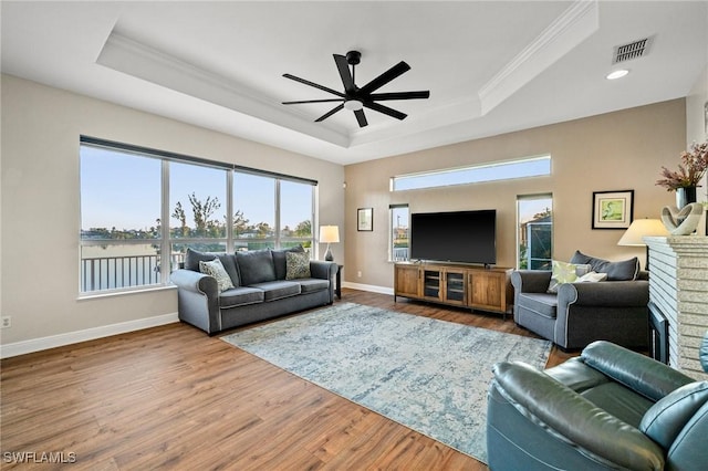 living room featuring ceiling fan, baseboards, a tray ceiling, and wood finished floors