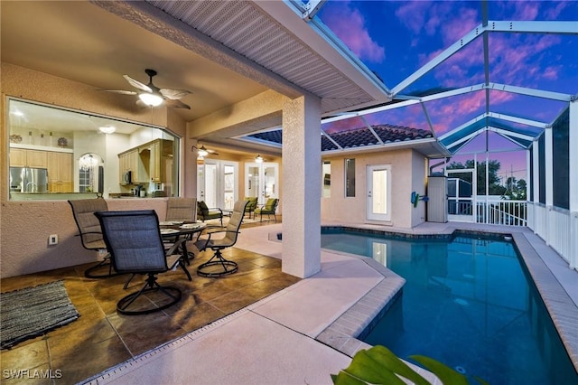 pool featuring glass enclosure, a patio, and a ceiling fan