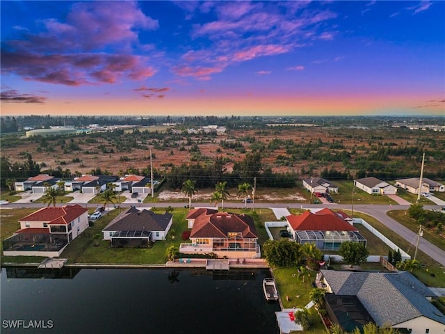 aerial view at dusk with a residential view and a water view