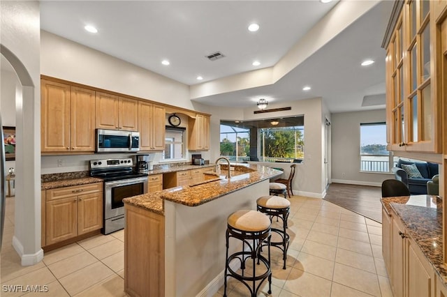 kitchen featuring dark stone countertops, a kitchen breakfast bar, visible vents, and appliances with stainless steel finishes