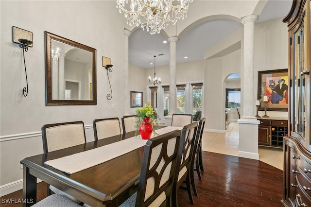 dining area featuring hardwood / wood-style floors, baseboards, an inviting chandelier, decorative columns, and arched walkways