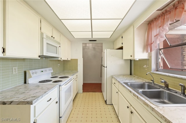 kitchen with light floors, light countertops, backsplash, a sink, and white appliances