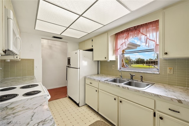 kitchen with white appliances, light countertops, a sink, and cream cabinetry