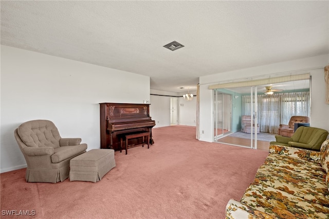 living area with carpet flooring, visible vents, a textured ceiling, and an inviting chandelier