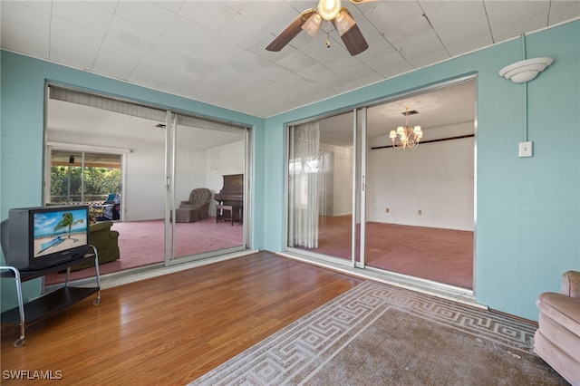 interior space featuring wood finished floors and ceiling fan with notable chandelier