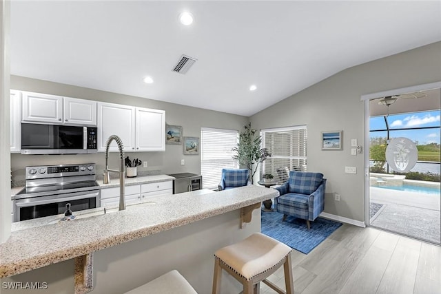 kitchen featuring plenty of natural light, visible vents, appliances with stainless steel finishes, and a kitchen breakfast bar