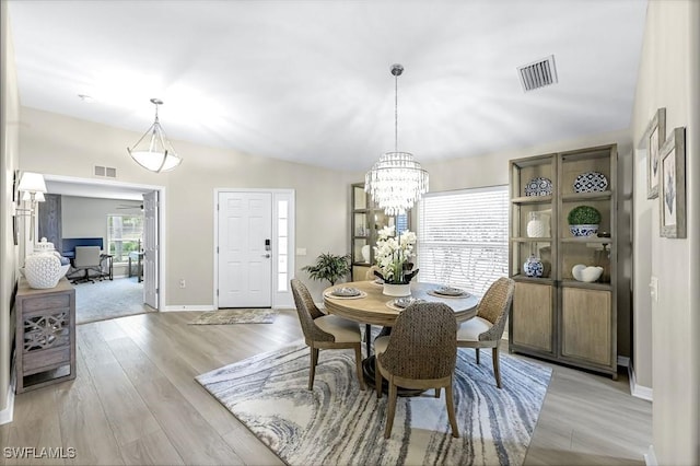 dining space featuring lofted ceiling, light wood-style flooring, visible vents, and baseboards