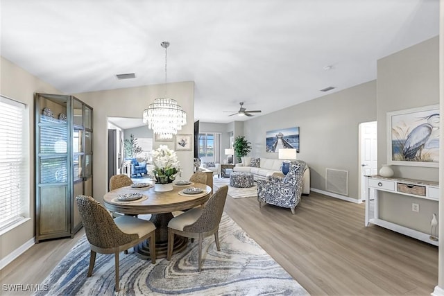 dining space with lofted ceiling, light wood finished floors, and visible vents