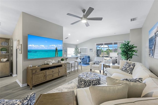 living area with ceiling fan, light wood-style flooring, visible vents, baseboards, and vaulted ceiling