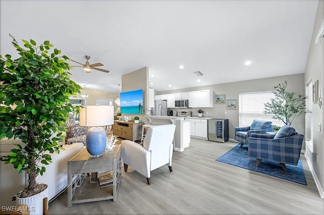 living room with recessed lighting, visible vents, light wood-style flooring, vaulted ceiling, and beverage cooler