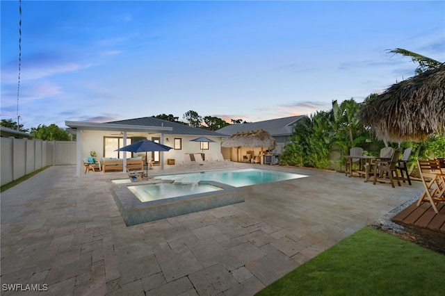 pool featuring a fenced backyard, an in ground hot tub, a storage structure, an outbuilding, and a patio area