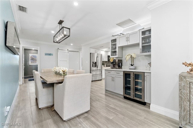 kitchen with a barn door, beverage cooler, visible vents, backsplash, and stainless steel fridge