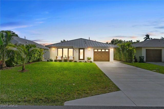 view of front of home with metal roof, a garage, driveway, stucco siding, and a standing seam roof