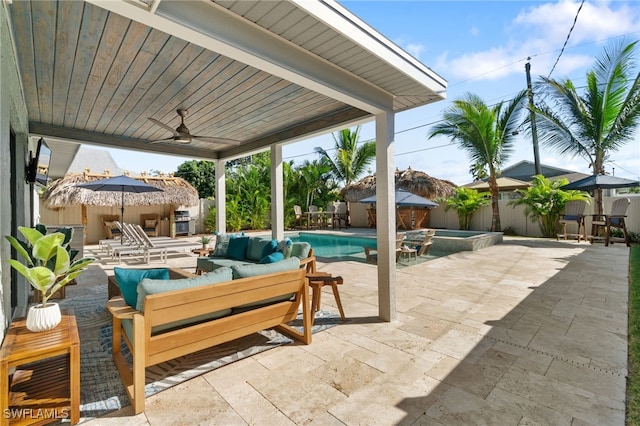 view of patio with an outbuilding, an outdoor hangout area, a ceiling fan, an in ground hot tub, and a fenced backyard