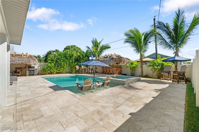 view of pool featuring a pool with connected hot tub, a patio area, and a fenced backyard