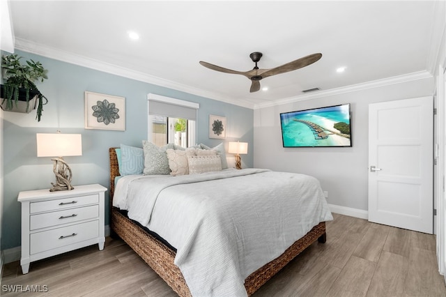 bedroom featuring baseboards, light wood-style flooring, visible vents, and crown molding