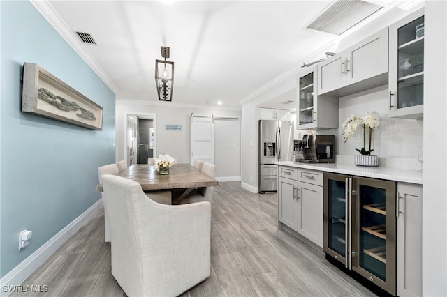 kitchen with crown molding, visible vents, a barn door, beverage cooler, and stainless steel fridge