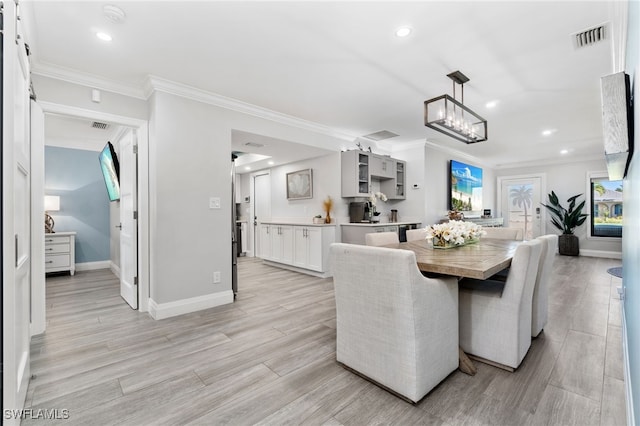 dining space with ornamental molding, visible vents, light wood-style floors, and baseboards