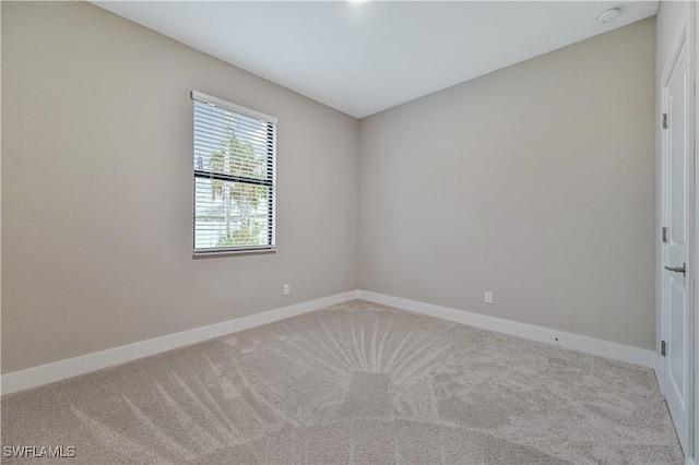 carpeted spare room featuring baseboards