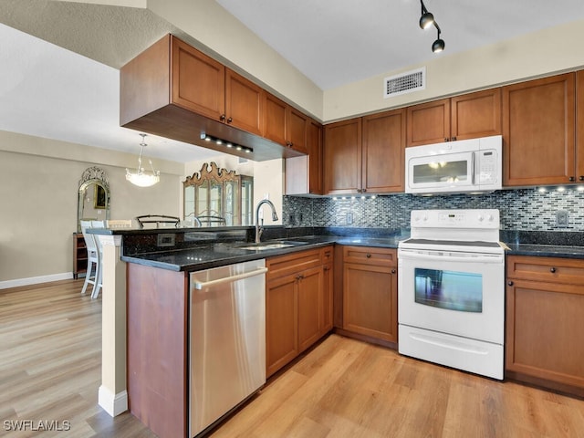 kitchen with light wood-style flooring, white appliances, a sink, visible vents, and brown cabinets