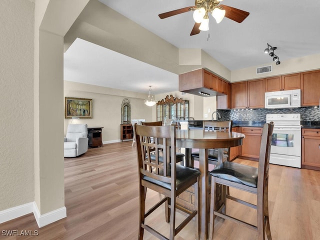 kitchen with white appliances, tasteful backsplash, visible vents, dark countertops, and light wood-style flooring