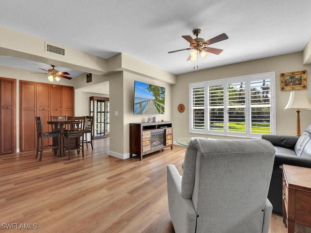 living room with light wood-type flooring, visible vents, plenty of natural light, and ceiling fan