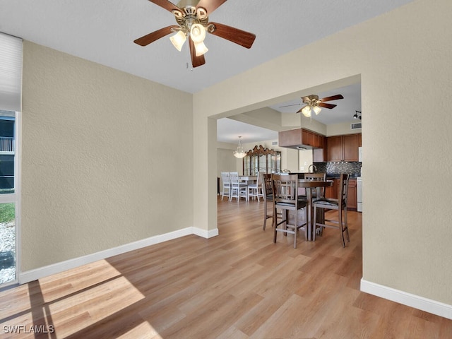 dining room featuring a textured wall, light wood-style flooring, and baseboards