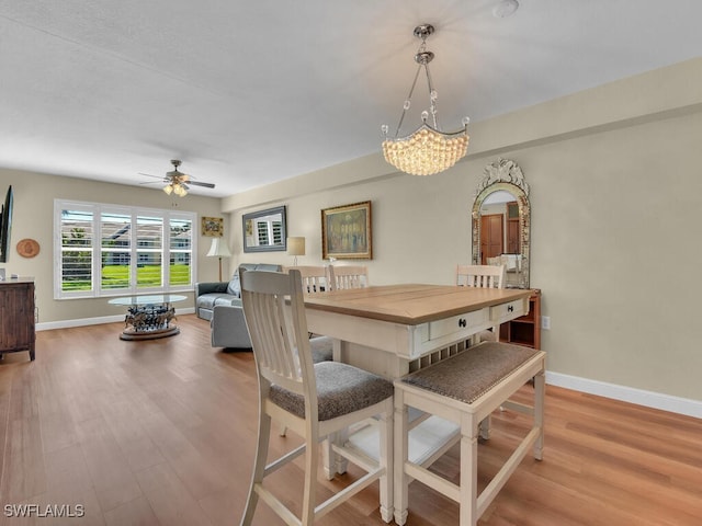 dining area featuring baseboards, wood finished floors, and ceiling fan with notable chandelier