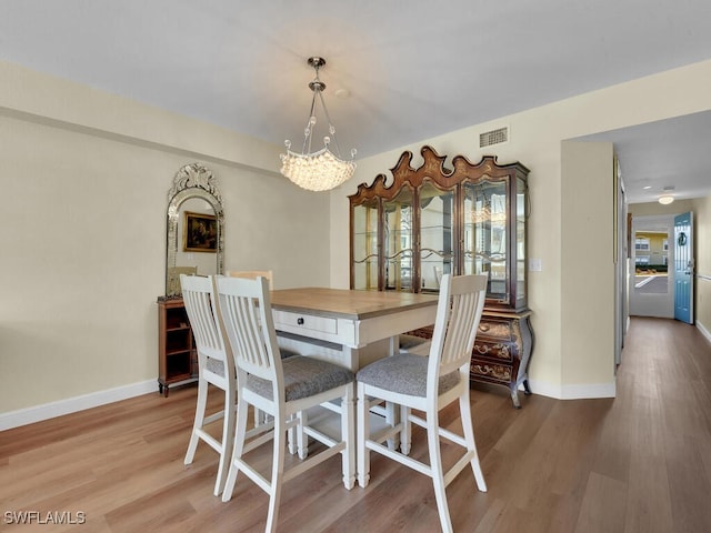 dining room with a chandelier, visible vents, baseboards, and wood finished floors