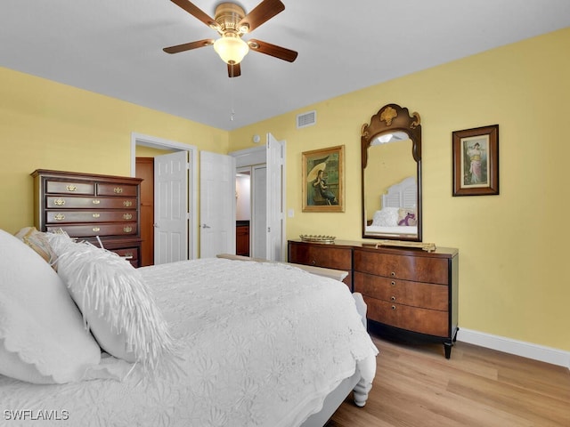 bedroom featuring a ceiling fan, wood finished floors, visible vents, and baseboards