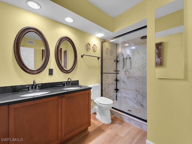 bathroom with a marble finish shower, a sink, toilet, and wood finished floors