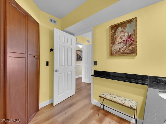 corridor with visible vents, light wood-style flooring, and baseboards