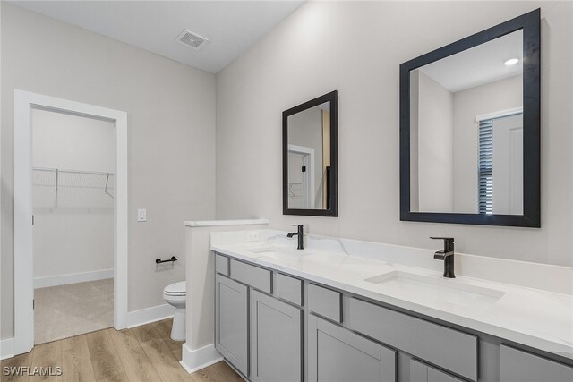 1705 SW 13th St, Cape Coral, FL 33991 - full bathroom with wood finished floors, toilet, double vanity, a spacious closet, and baseboards
