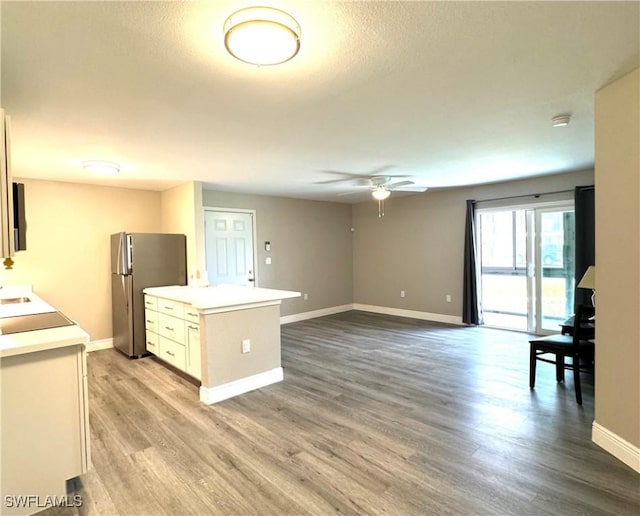 kitchen with ceiling fan, baseboards, light countertops, freestanding refrigerator, and light wood-style floors