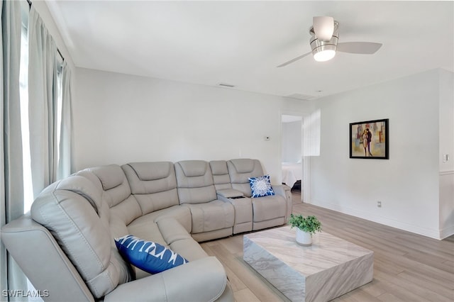 living room featuring baseboards, ceiling fan, visible vents, and light wood finished floors