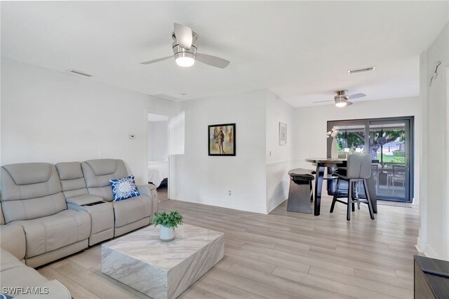 living room featuring ceiling fan, baseboards, visible vents, and light wood-style floors