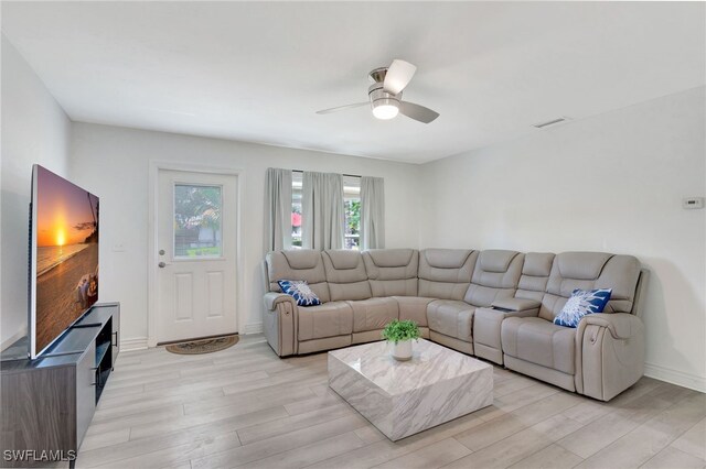 living area featuring baseboards, visible vents, a ceiling fan, and light wood-style floors