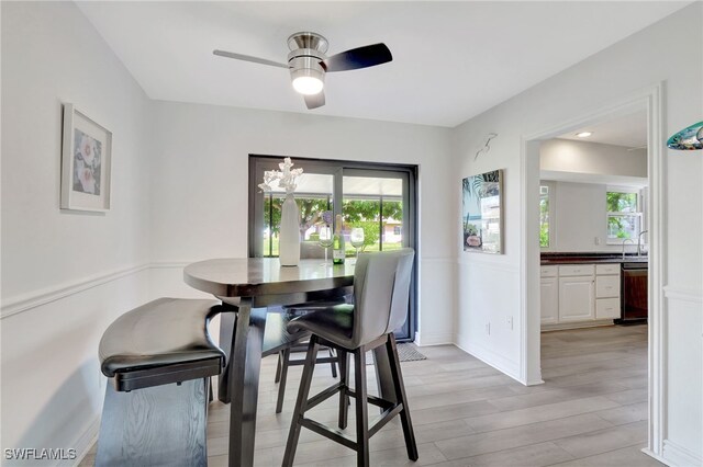 dining space featuring ceiling fan, light wood finished floors, a wealth of natural light, and baseboards