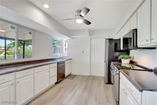 kitchen with stainless steel appliances, dark countertops, white cabinets, and light wood-style flooring