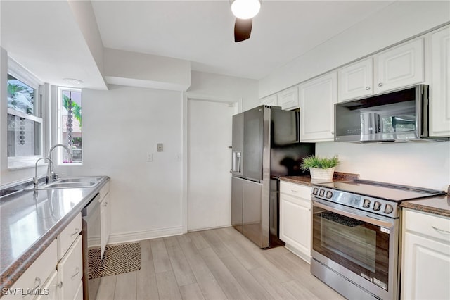 kitchen featuring stainless steel appliances, light wood-style flooring, a sink, and white cabinetry