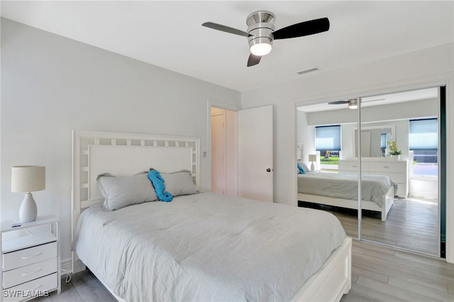 bedroom with light wood-type flooring, a ceiling fan, visible vents, and a closet