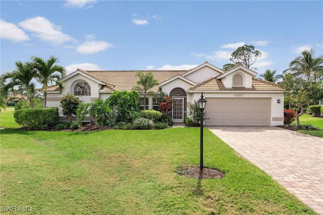 view of front of house featuring a front lawn, decorative driveway, an attached garage, and stucco siding