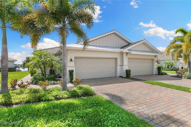 view of front facade with board and batten siding, decorative driveway, and an attached garage