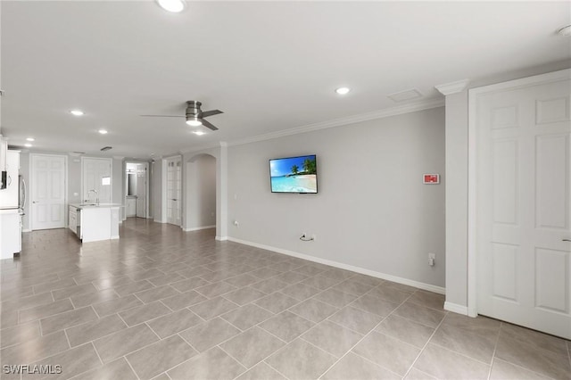 unfurnished living room with a ceiling fan, arched walkways, crown molding, and baseboards