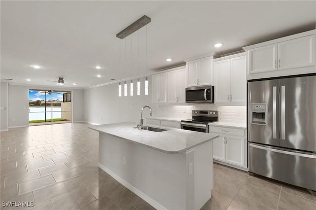 kitchen with appliances with stainless steel finishes, open floor plan, a sink, backsplash, and light tile patterned flooring