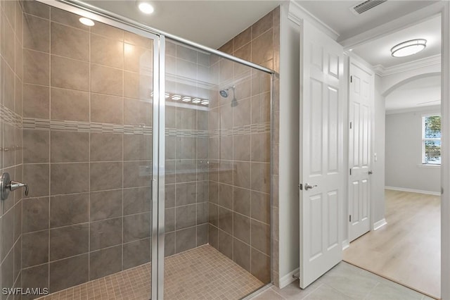 bathroom featuring visible vents, ornamental molding, a stall shower, tile patterned flooring, and baseboards